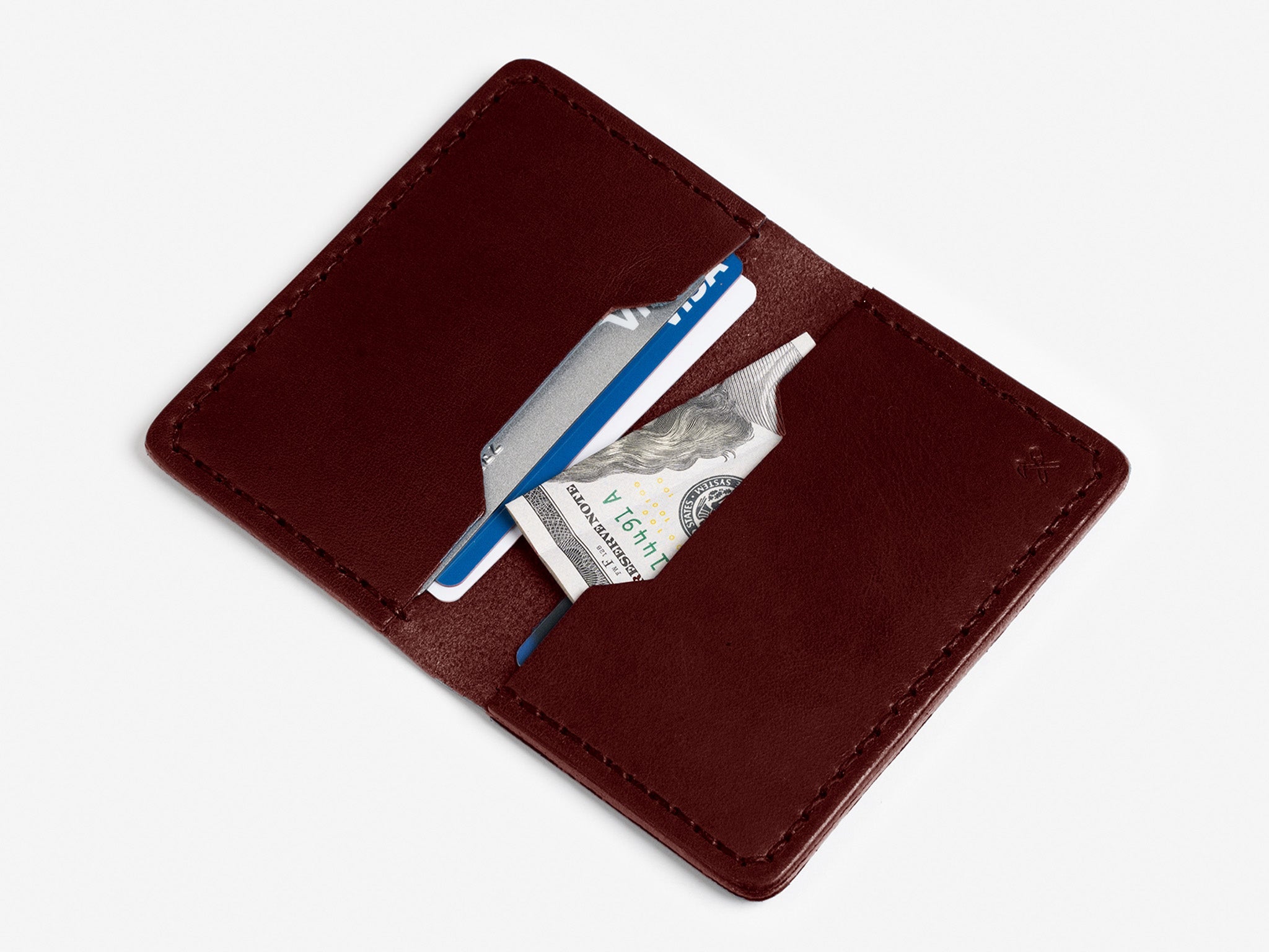A brown leather wallet open to show a blue credit card, a silver card, and a folded U.S. $100 bill in its card slots, set against a white background.